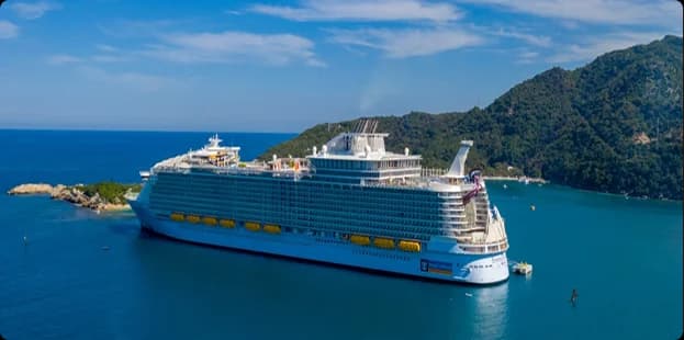 Luxury cruise ship sailing on clear blue ocean near tropical islands